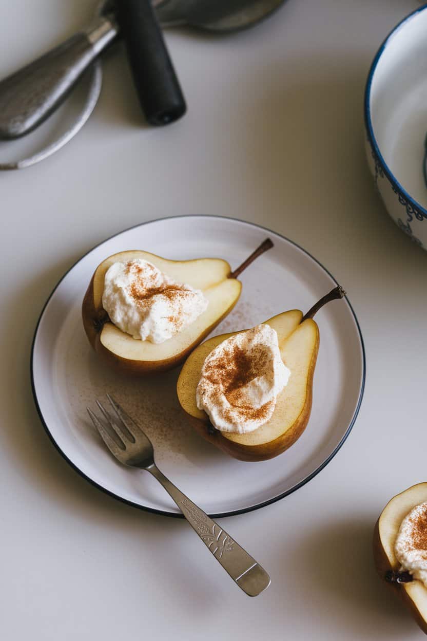  An indoor kitchen counter displaying pear halves filled with creamy ricotta and dusted with cinnamon, small dessert fork nearby—no text or brands.