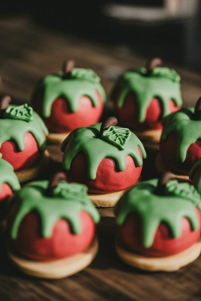 Indoor photo of small round red cookies with dripping green icing “poison” over the top, grouped in a circle, no text or logos.