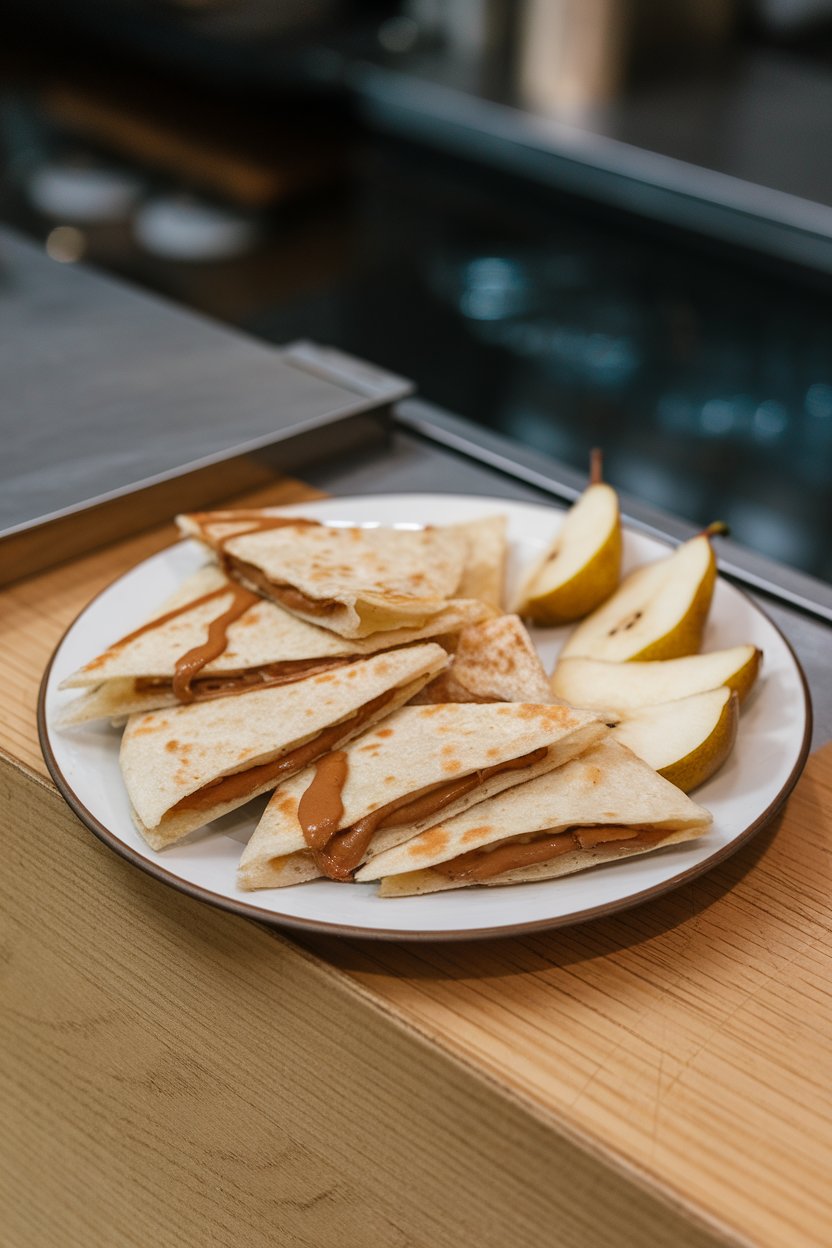 A white plate on an indoor snack bar showing triangular quesadilla wedges with pear slices and almond butter oozing slightly. No logos. Photo.