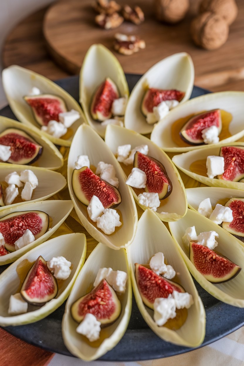 A platter indoors of endive leaves filled with chopped figs and goat cheese crumbles, drizzled honey visible; no text or logos, photo only